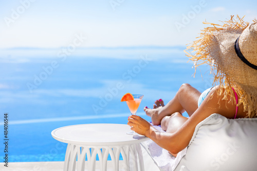Woman relaxing by infinity pool with beautiful sea view