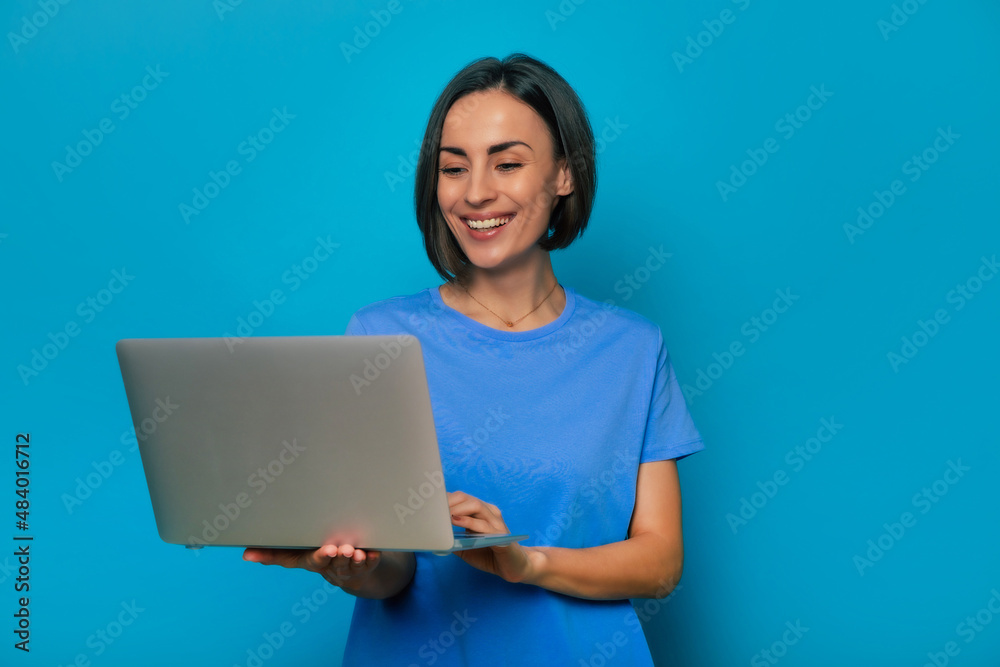 Close up portrait of beautiful smiling stylish smart woman with modern gray laptop in hands while she using it and surfing in the network for study or work Close up portrait of beautiful smiling stylish smart woman with modern gray laptop in hands while she using it and surfing in the network for study or work