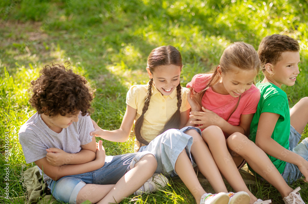 Smiling children sitting on grass in park Smiling children sitting on grass in park