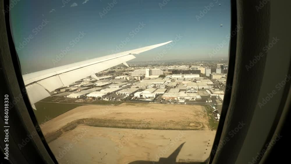 Aerial view from airplane window porthole during landing in Los Angeles, LAX. Beautiful view from airplane window. Ultra wide-angle POV shot from a window seat of an airplane. 