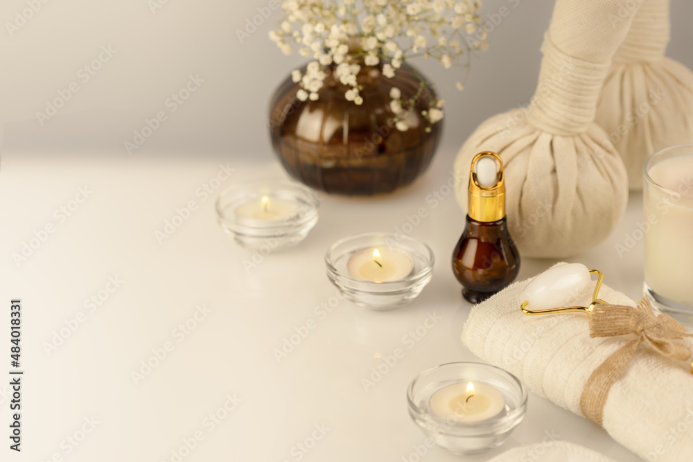 Spa relax massage procedure. Wellbeing cosmetology still life with spa accessories, serum, candles and towel on a white table. Wellness and skin care treatment. Concept of me time and no depression Spa relax massage procedure. Wellbeing cosmetology still life with spa accessories, serum, candles and towel on a white table. Wellness and skin care treatment. Concept of me time and no depression