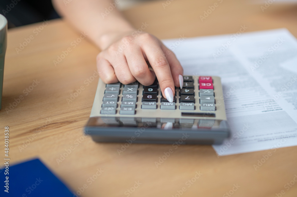 Bookkeeper seated at the office desk using a pocket calculator Bookkeeper seated at the office desk using a pocket calculator