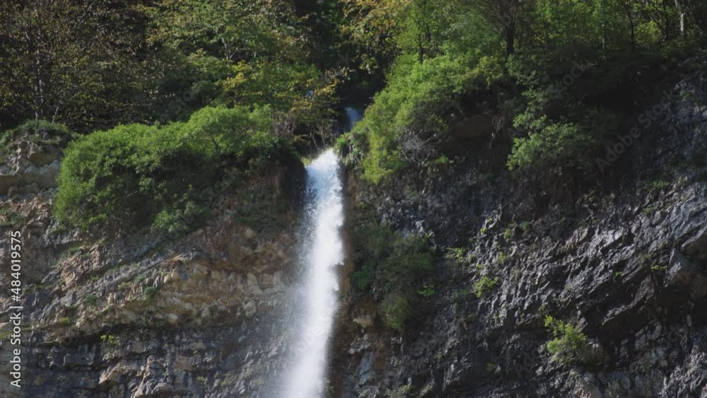 River stream falling from the high cliff between the trees. Slow motion. River stream falling from the high cliff between the trees. Slow motion.