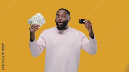 African American man shows cash or credit card. money banknotes and card, african american man guy with success in cash financial freedom on yellow background photo