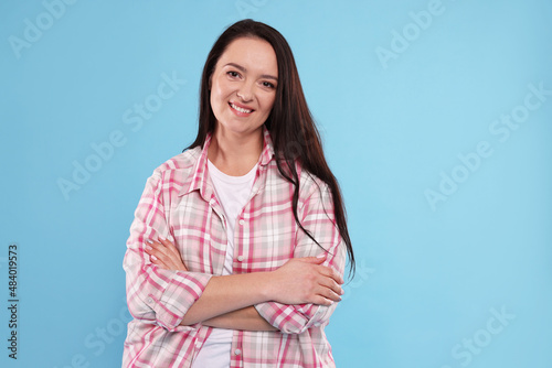 Beautiful overweight woman with charming smile on turquoise background