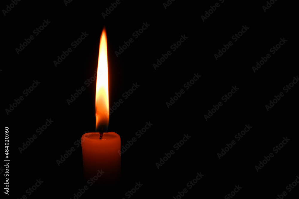 Candle flame on black background. Single lit candle with quite flame. Dramatic burning candle flame on a black background with copy space Candle flame on black background. Single lit candle with quite flame. Dramatic burning candle flame on a black background with copy space