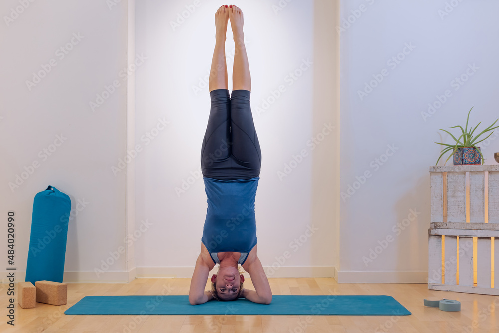 shirshasana yoga position - yoga teacher performs exercises on the mat