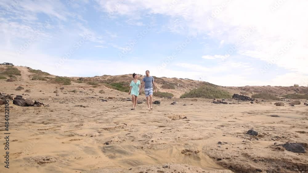 Happy couple in love spending time together at seaside in Fuerteventura walking and holding hands Happy couple in love spending time together at seaside in Fuerteventura walking and holding hands