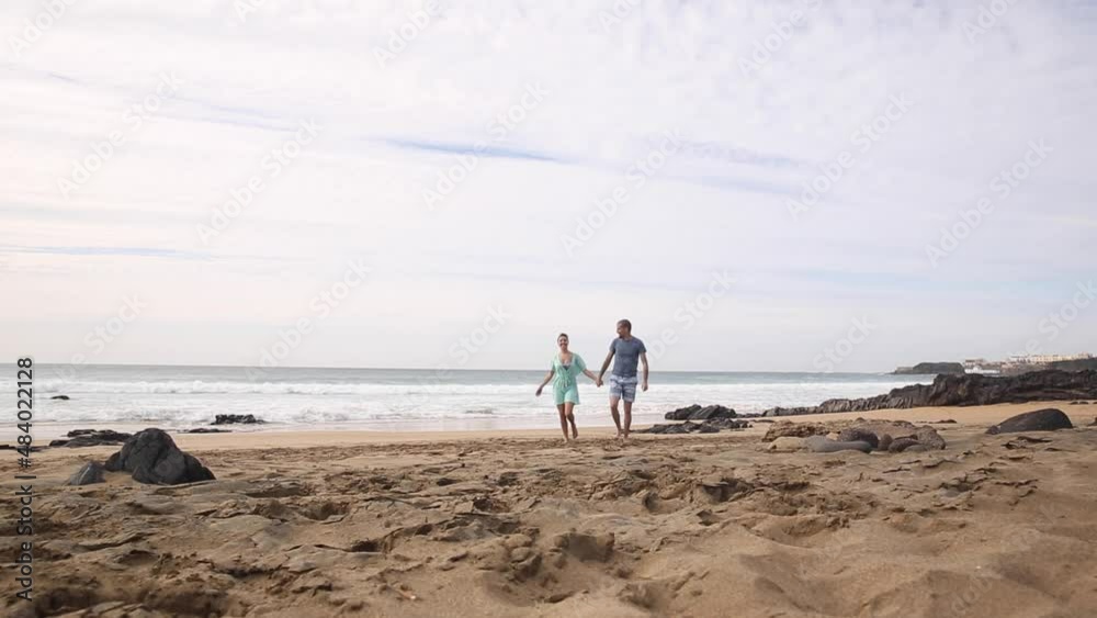 Happy couple in love spending time together at seaside in Fuerteventura walking and holding hands Happy couple in love spending time together at seaside in Fuerteventura walking and holding hands