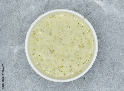 Raita with mint, herbs and onion in a bowl top view on dark grey background indian pakistani food