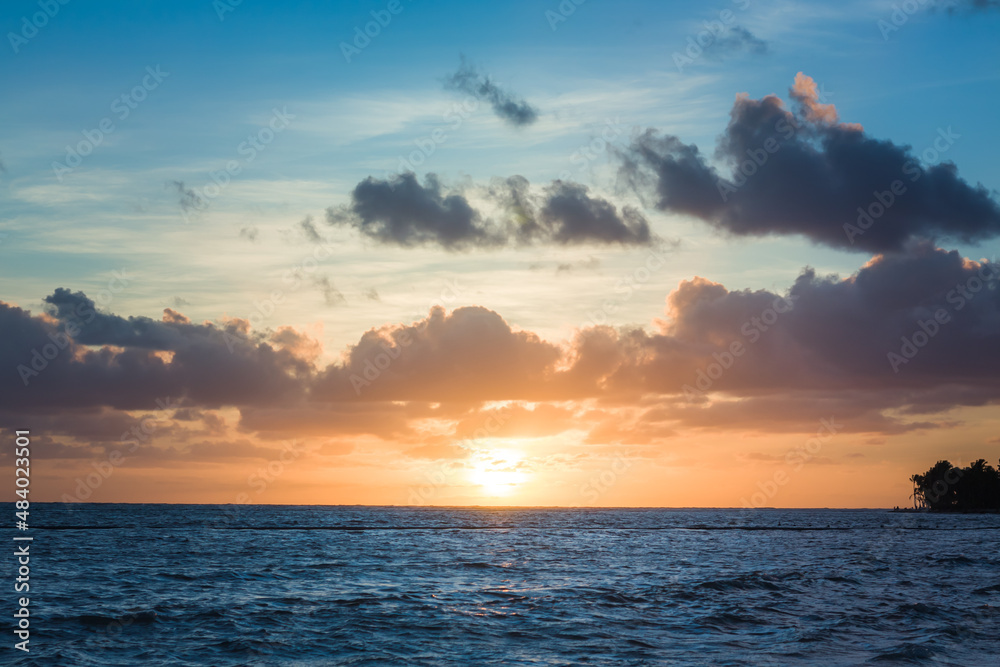 Fototapeta premium Beautiful sunrise at sea. Dawn on the Atlantic ocean. The sun is reflected in the sea. Palm trees against the background of the rising sun. Tropical sunrise. Dominican Republic
