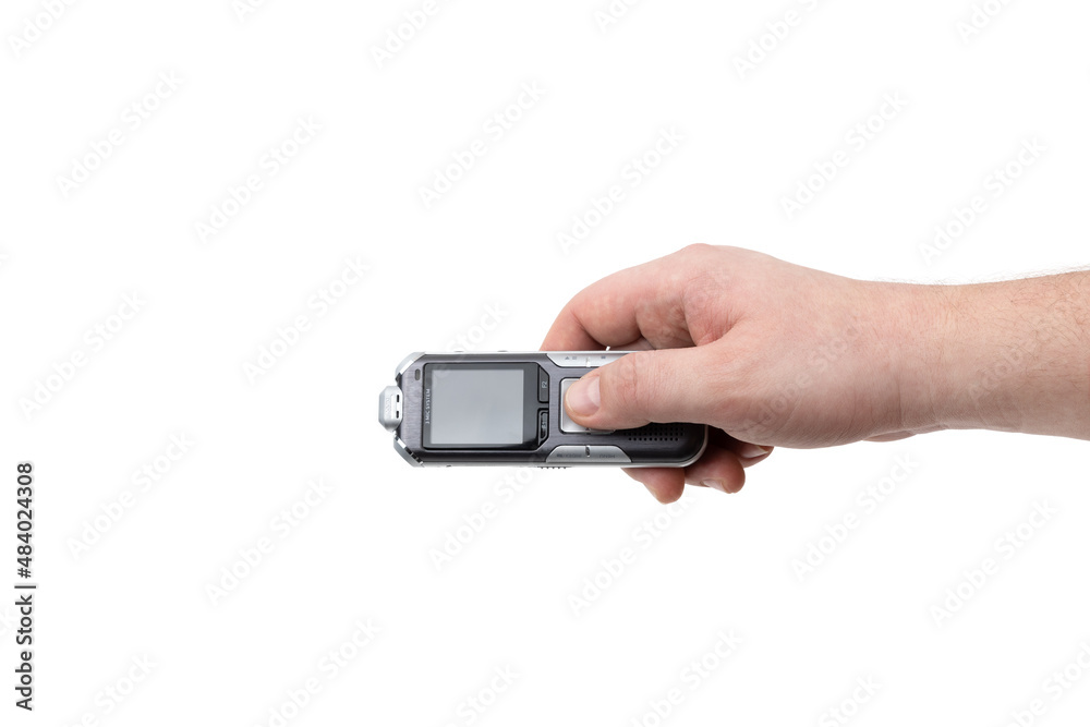 The voice recorder is isolated on a white background. Dictaphone in hand close-up on a white background. The voice recorder is isolated on a white background. Dictaphone in hand close-up on a white background.