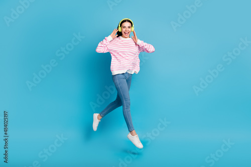 Full body photo of young lady active jump listen radio earphones meloman isolated over blue color background