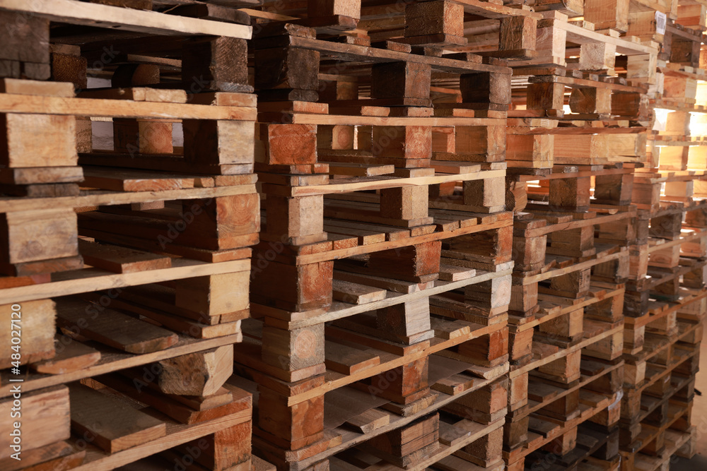 Many empty wooden pallets stacked in warehouse Many empty wooden pallets stacked in warehouse