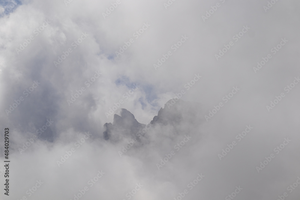 Naklejka premium Clouds almost comletly covering the sharp mountain peaks of the Chaukhi massif in the Greater Caucasus Mountain Range in Georgia, Kazbegi Region. Hiking. Georgian Dolomites. Cloudscape