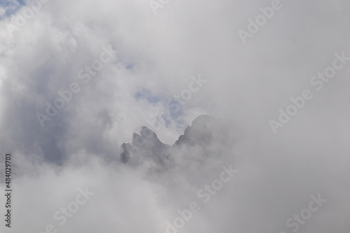 Clouds almost comletly covering the sharp mountain peaks of the Chaukhi massif in the Greater Caucasus Mountain Range in Georgia, Kazbegi Region. Hiking. Georgian Dolomites. Cloudscape