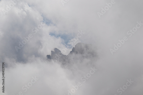 Clouds almost comletly covering the sharp mountain peaks of the Chaukhi massif in the Greater Caucasus Mountain Range in Georgia, Kazbegi Region. Hiking. Georgian Dolomites. Cloudscape
