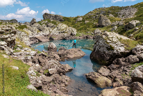 A man enjoying the Colorful Abudelauri mountain lakes in the Greater Caucasus Mountain Range in Georgia,Kazbegi Region. Trekking and outdoor travel.Alpine pastures.Backpacking and trekking.Green lake