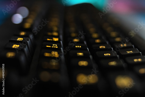 RGB computer keyboard displaying yellow colors, macro photo in the dark