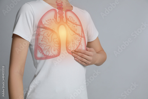 Woman holding hand near chest with illustration of lungs on light grey background, closeup photo