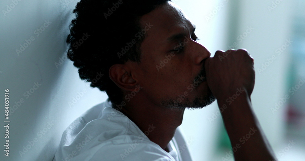 Worried black man feeling distraught and preoccupied sitting on home floor, suffering african american person Stock Photo | Adobe Stock