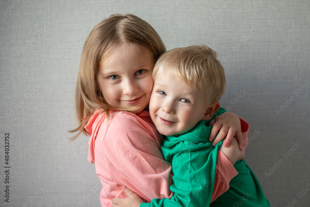 close-up portrait of two children happy and smiling. Blonde brother and sister hugging, sibling relationship concept. funny kids. Boy and girl hugging close-up portrait of two children happy and smiling. Blonde brother and sister hugging, sibling relationship concept. funny kids. Boy and girl hugging