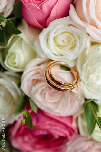 Golden rings of the newlyweds between white shoes with heels. Precious rings of the bride and groom