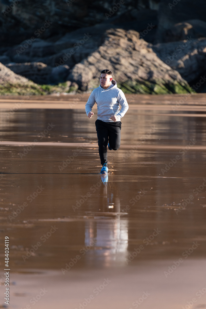 Latin man running at the beach. Goals achievement motivation and loosing weight concept. 