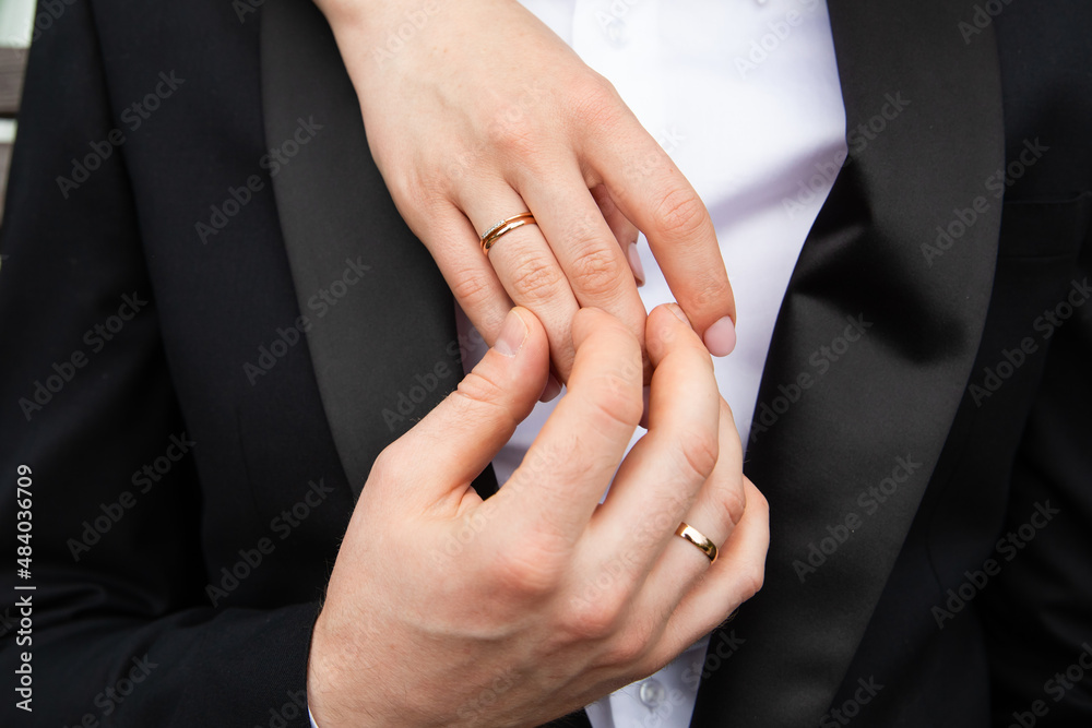 A pair of gold wedding rings on bride and groom hands