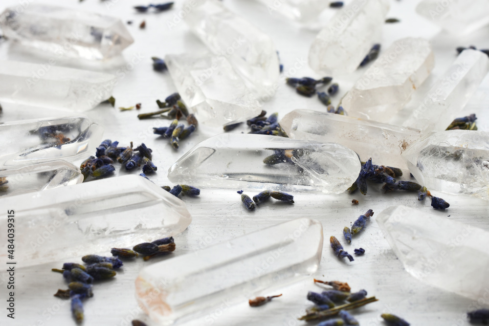A close up image of several clear quartz crystal points with dried lavender flowers on a white background.  - obrazy, fototapety, plakaty 