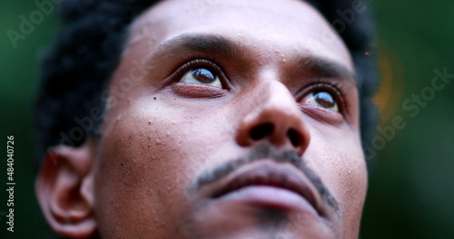 Contemplative man closing eyes. Close-up face portrait of mixed race person meditating outside