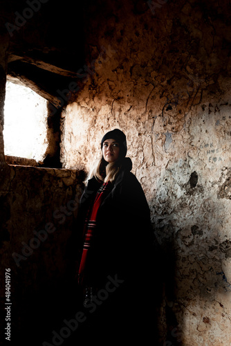 фотографія A girl in front of the window in the dark historical abandoned house