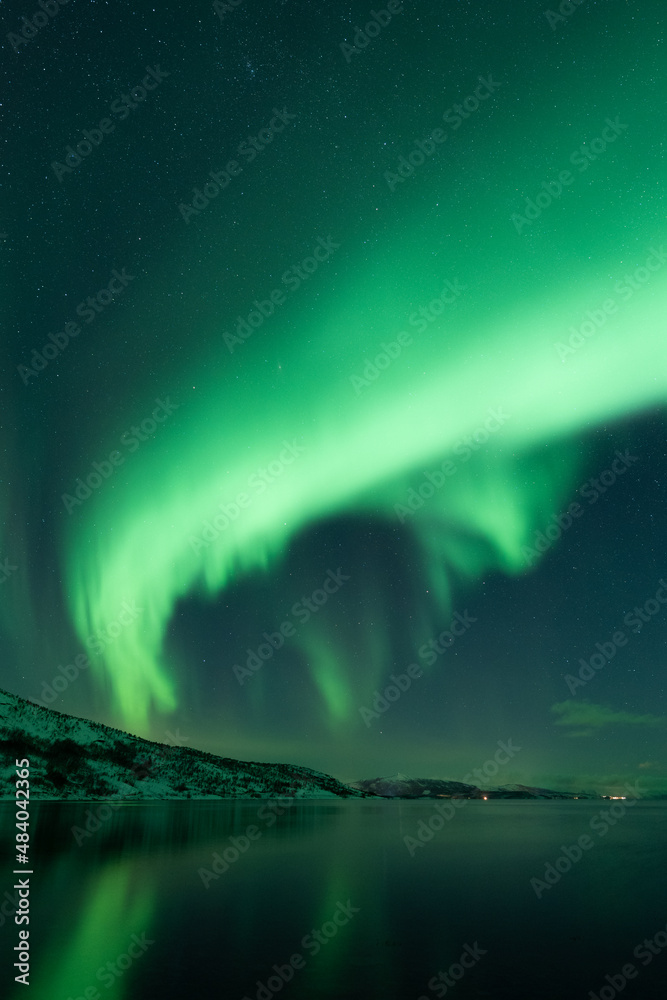 Aurora borealis portrait of powerful burst of green light over the flat sea