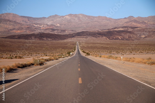 Looking down the middle of a long straight desert road with no one in site for miles in the Death Valley
