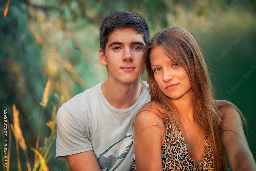 Loving and happy guy and girl are sitting on the lake in the forest. Lovers in an embrace celebrating Valentine's Day. Loving and happy guy and girl are sitting on the lake in the forest. Lovers in an embrace celebrating Valentine's Day.
