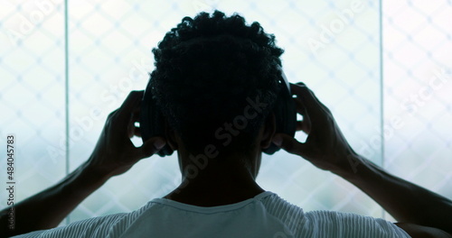 Back of black guy listening to song, man removes headphone and music stops