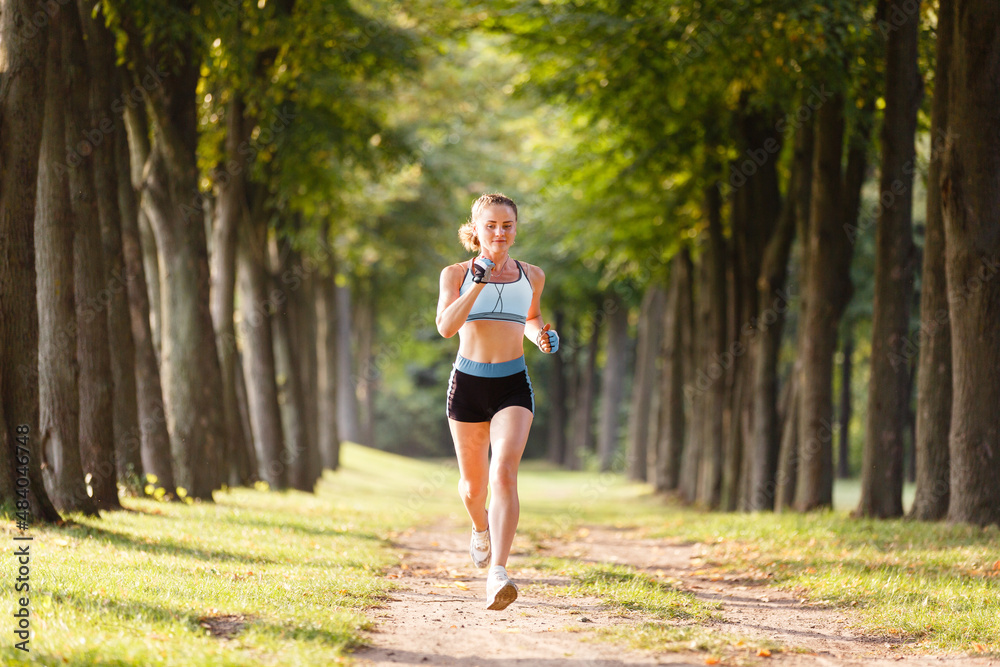 sport girl is running outdoors weared in sports wear. Young sport woman stretching in a park. Fitness workout for body. Outdoor fitness. Healthy lifestyle practice. Athlete running outdoors sport girl is running outdoors weared in sports wear. Young sport woman stretching in a park. Fitness workout for body. Outdoor fitness. Healthy lifestyle practice. Athlete running outdoors