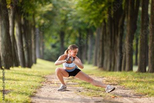 sport girl is running outdoors weared in sports wear. Young sport woman stretching in a park. Fitness workout for body. Outdoor fitness. Healthy lifestyle practice. Athlete running outdoors