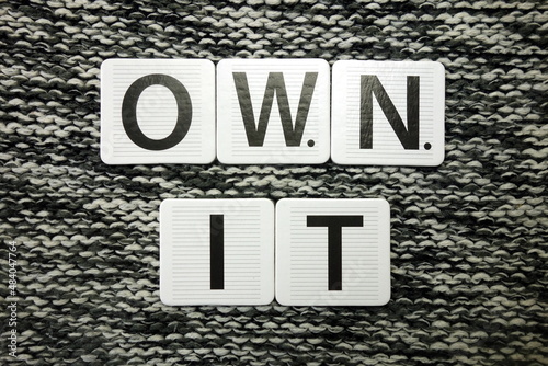 Words own it on dark background. Taking ownership concept