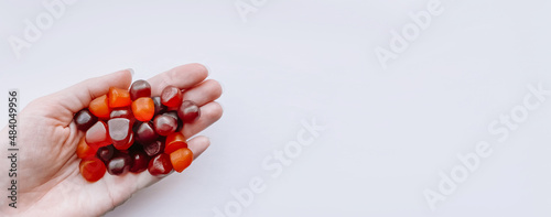 Group of red, orange and purple multivitamin gummies in the hand isolated on white background photo