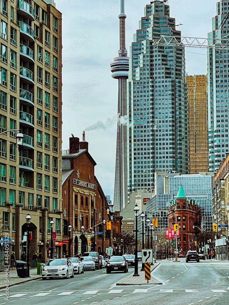 Obraz premium The long-distance view of the CN Tower sharing with many buildings on a sunny day.