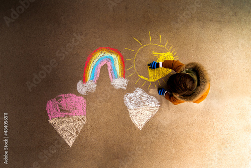 a child making artwork with chalk on a sidewalk photo