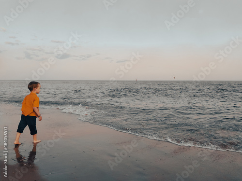Little boy looks at the sea on the beach photo