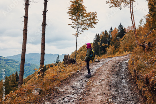 Woman mountain tourist standing in autumn mountain forest.