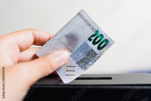 Guardando uma nota de R$ 200,00 no cofre photo