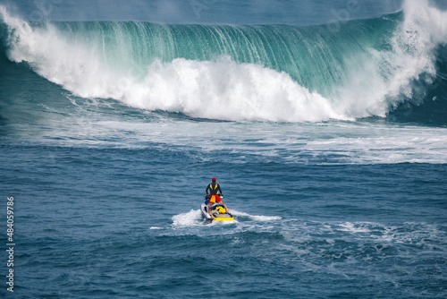 Rescue lifeguard in the ocean in front of a big wave on a jet ski searching for surfers photo