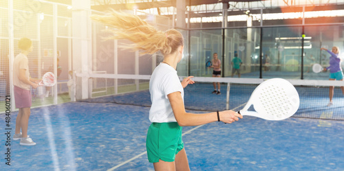 Portrait of a confident fifteen-year-old girl tennis player engaged in the popular sport of padel with a racket indoors photo