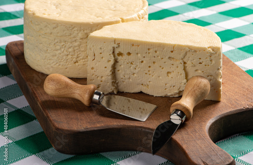 Semi-cured cheese from Brazil arranged on a rustic board on a green and white checkered tablecloth, selective focus. photo