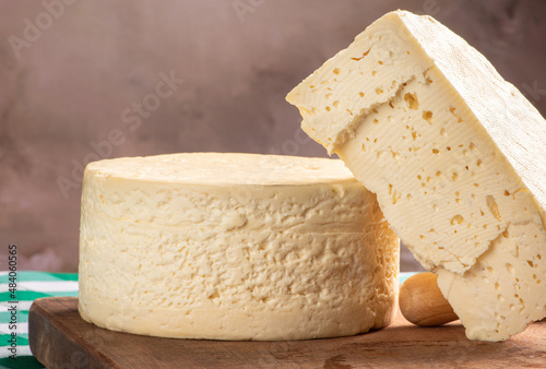 Semi-cured cheese from Brazil arranged on a rustic board on a green and white checkered tablecloth, selective focus.