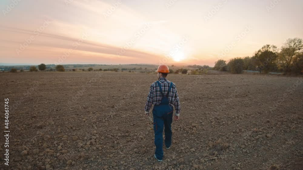 At sunlight shot back a man farmer hold tablet computer walk on field. Digital economy in agribusiness. Agricultural industry. Slow motion At sunlight shot back a man farmer hold tablet computer walk on field. Digital economy in agribusiness. Agricultural industry. Slow motion